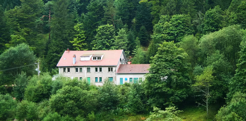 Foto van 'Centre de Vacances le Luschpach' op afstand, een groepsaccomodatie in Plainfaing, Frankrijk. Het chalet ligt in de Vogezen en staat bekend om de natuurlijke omgeving.