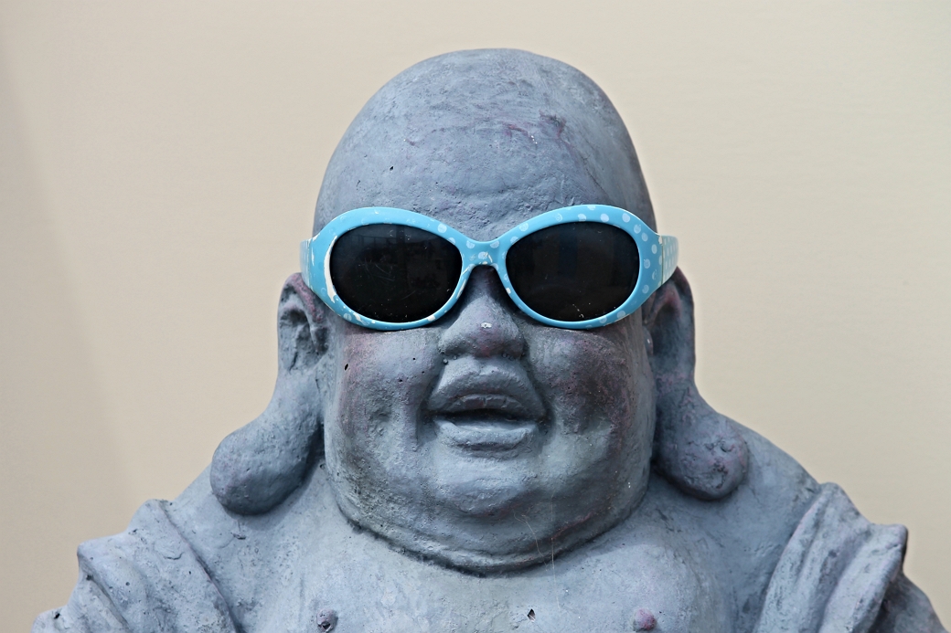 Lachende Boeddha beeld met babyblauwe en wit gestipte zonnebril